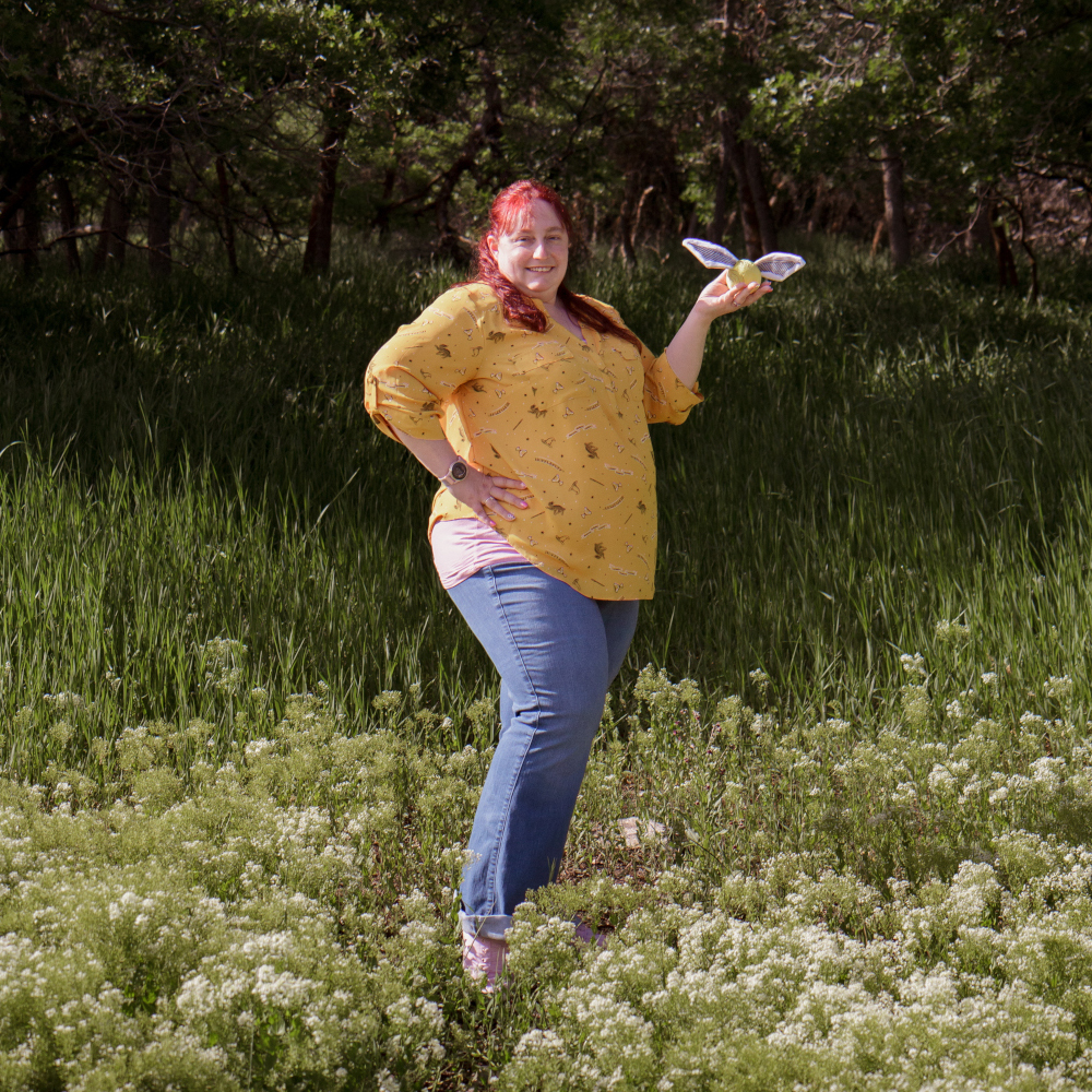 Lisa standing with golden snitch in a yellow shirt